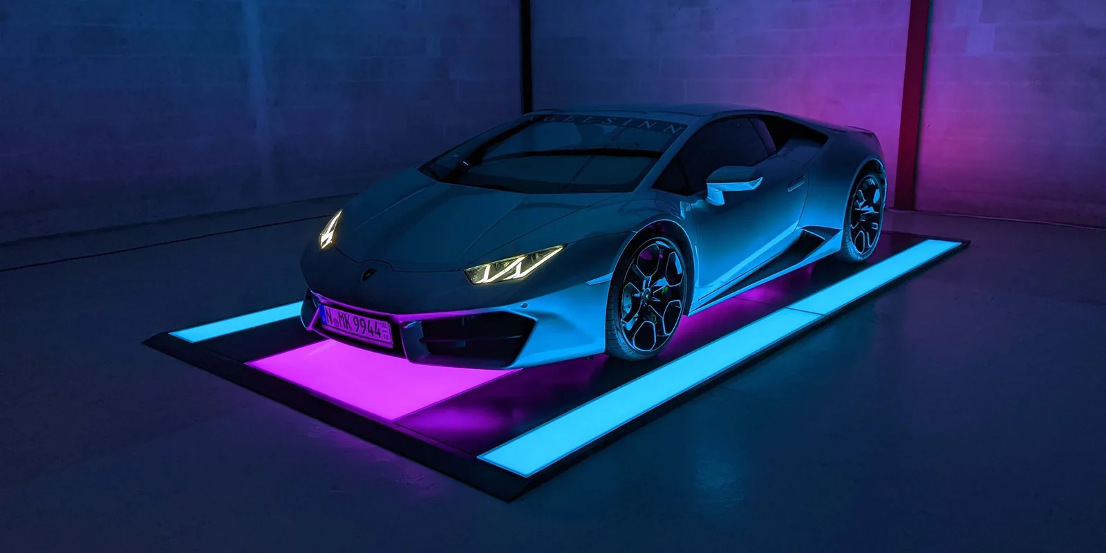 A supercar on a CarThrone lit magenta and cyan
